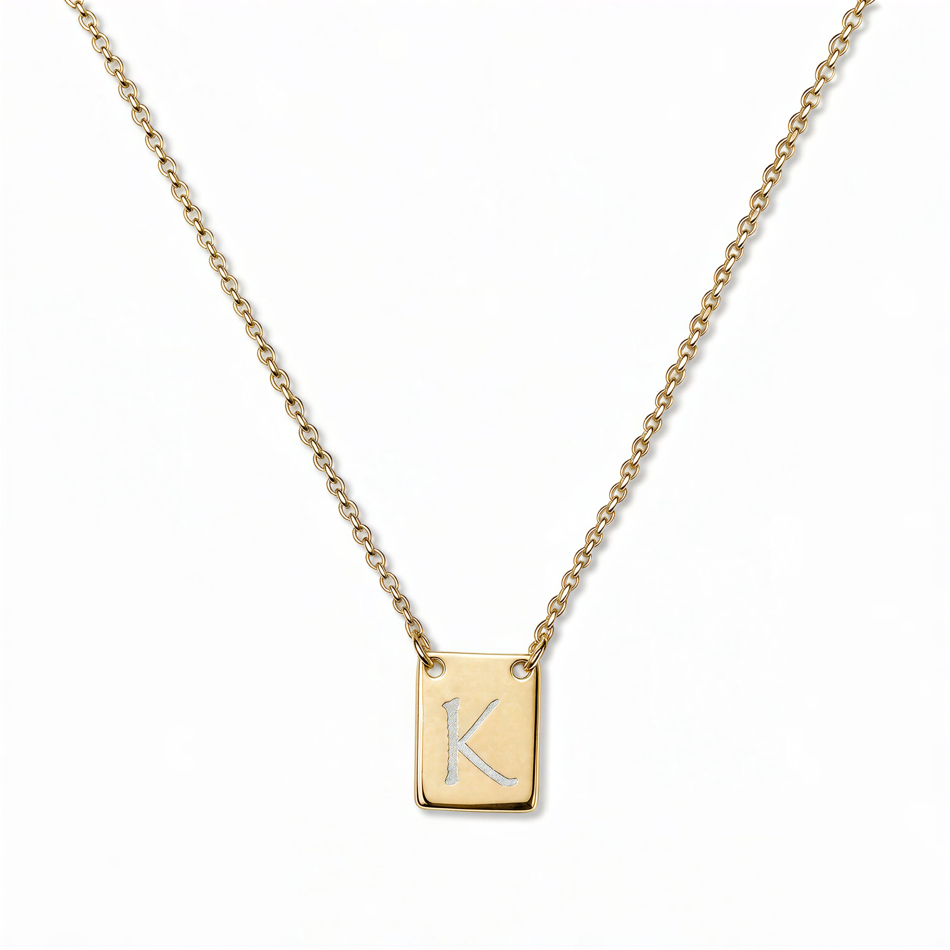 An Engraved Initial Necklace Letter K by Skōsh Jewelry, featuring a small rectangular tag engraved with the letter K on a fine gold chain, displayed against a white background.