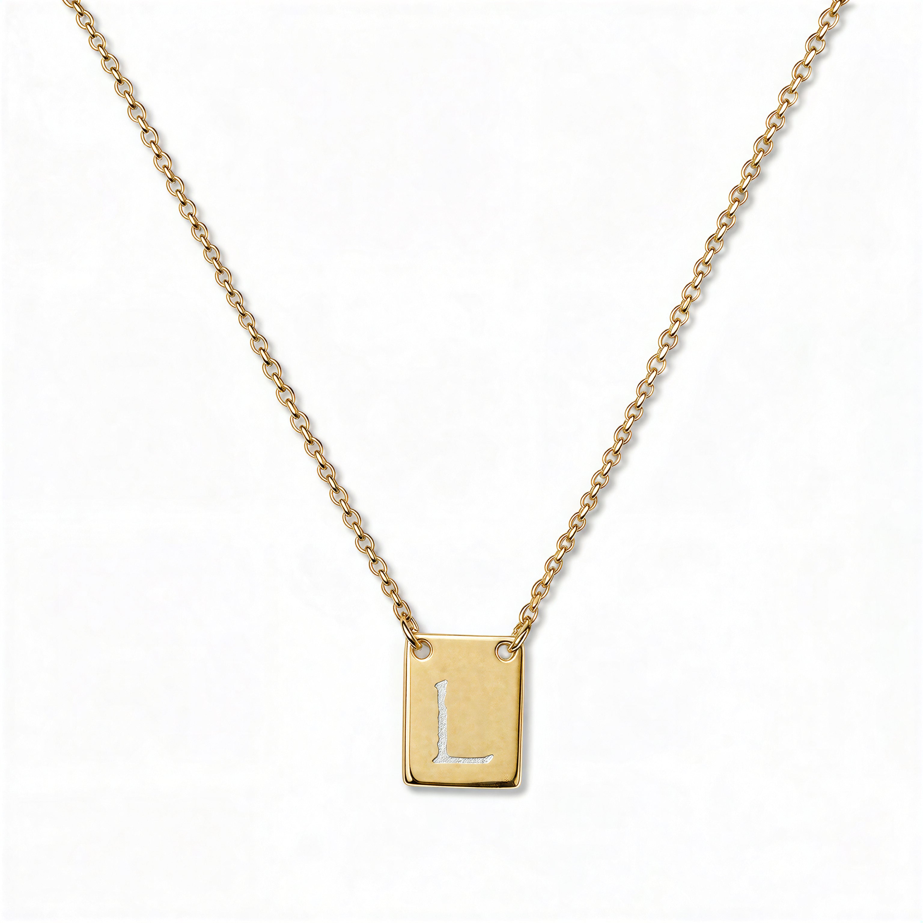 An Engraved Initial Necklace Letter L by Skōsh Jewelry, featuring a small rectangular tag engraved with the letter L on a fine gold chain, displayed against a white background.