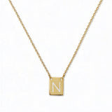 An Engraved Initial Necklace Letter N by Skōsh Jewelry, featuring a small rectangular tag engraved with the letter N on a fine gold chain, displayed against a white background.