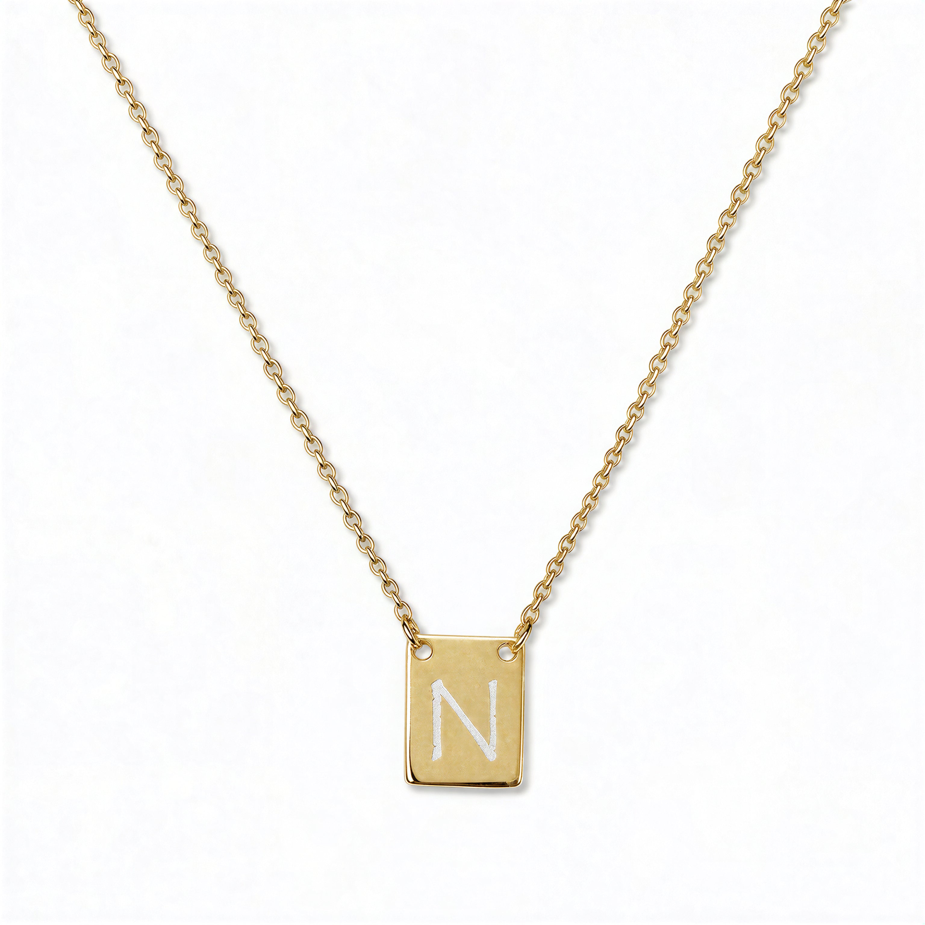 An Engraved Initial Necklace Letter N by Skōsh Jewelry, featuring a small rectangular tag engraved with the letter N on a fine gold chain, displayed against a white background.