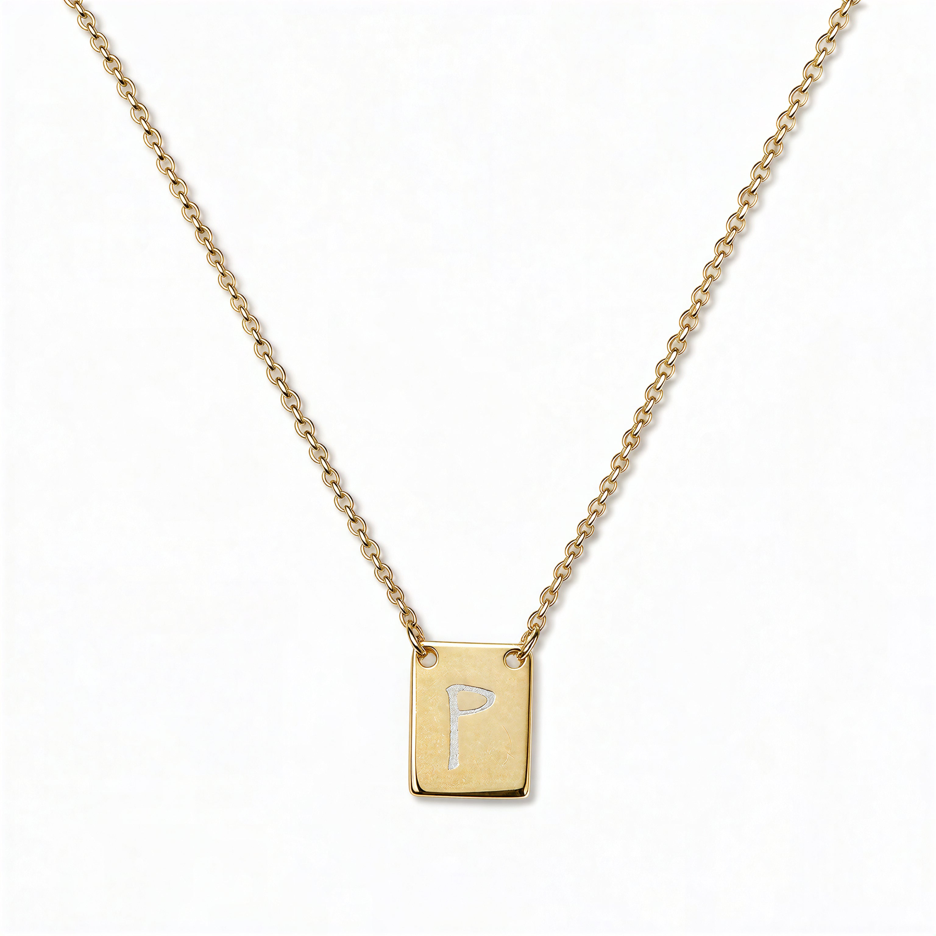 An Engraved Initial Necklace Letter P by Skōsh Jewelry, featuring a small rectangular tag engraved with the letter P on a fine gold chain, displayed against a white background.