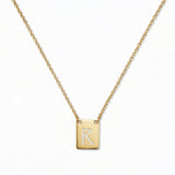 An Engraved Initial Necklace Letter R by Skōsh Jewelry, featuring a small rectangular tag engraved with the letter R on a fine gold chain, displayed against a white background.