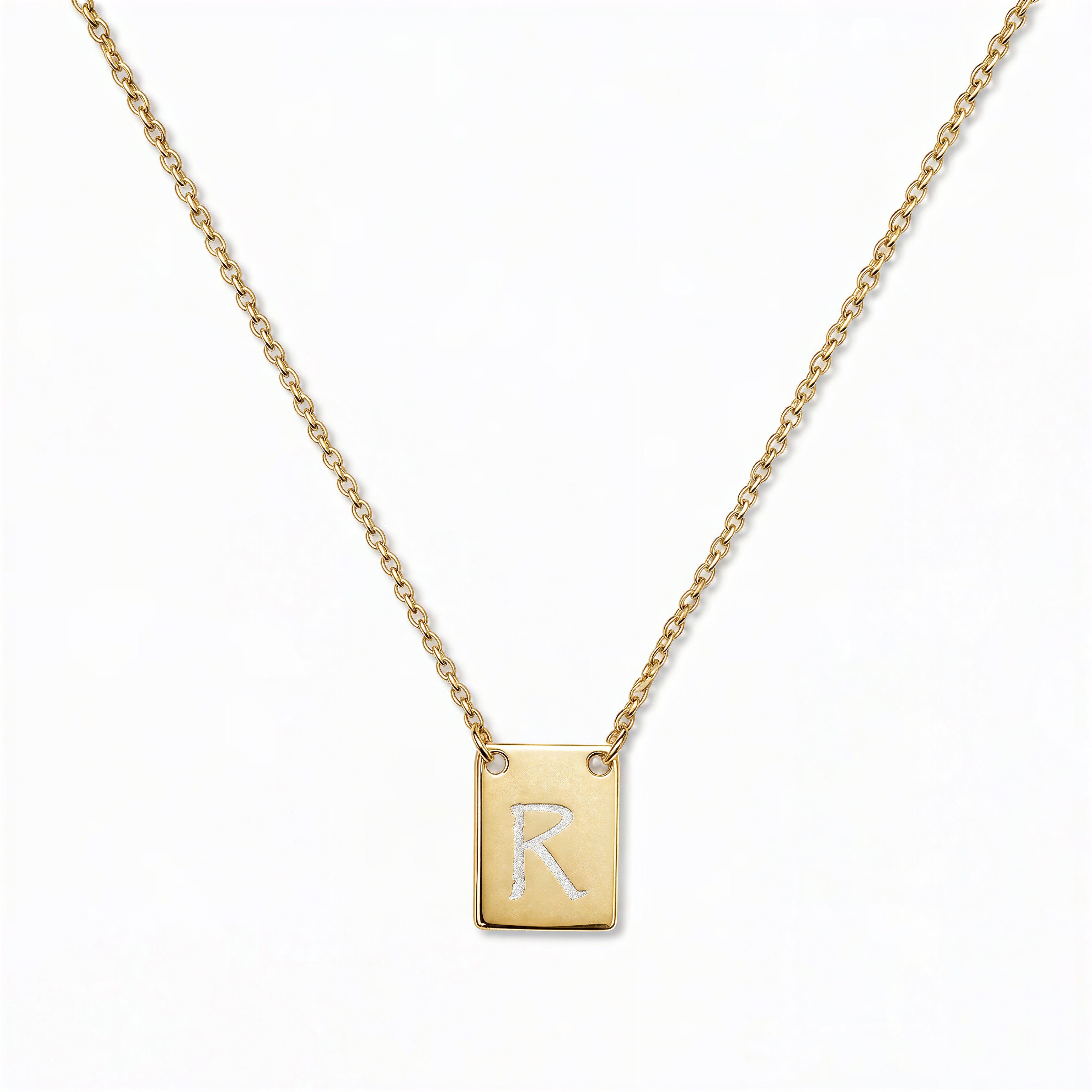An Engraved Initial Necklace Letter R by Skōsh Jewelry, featuring a small rectangular tag engraved with the letter R on a fine gold chain, displayed against a white background.