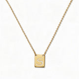 An Engraved Initial Necklace Letter S by Skōsh Jewelry, featuring a small rectangular tag engraved with the letter S on a fine gold chain, displayed against a white background.