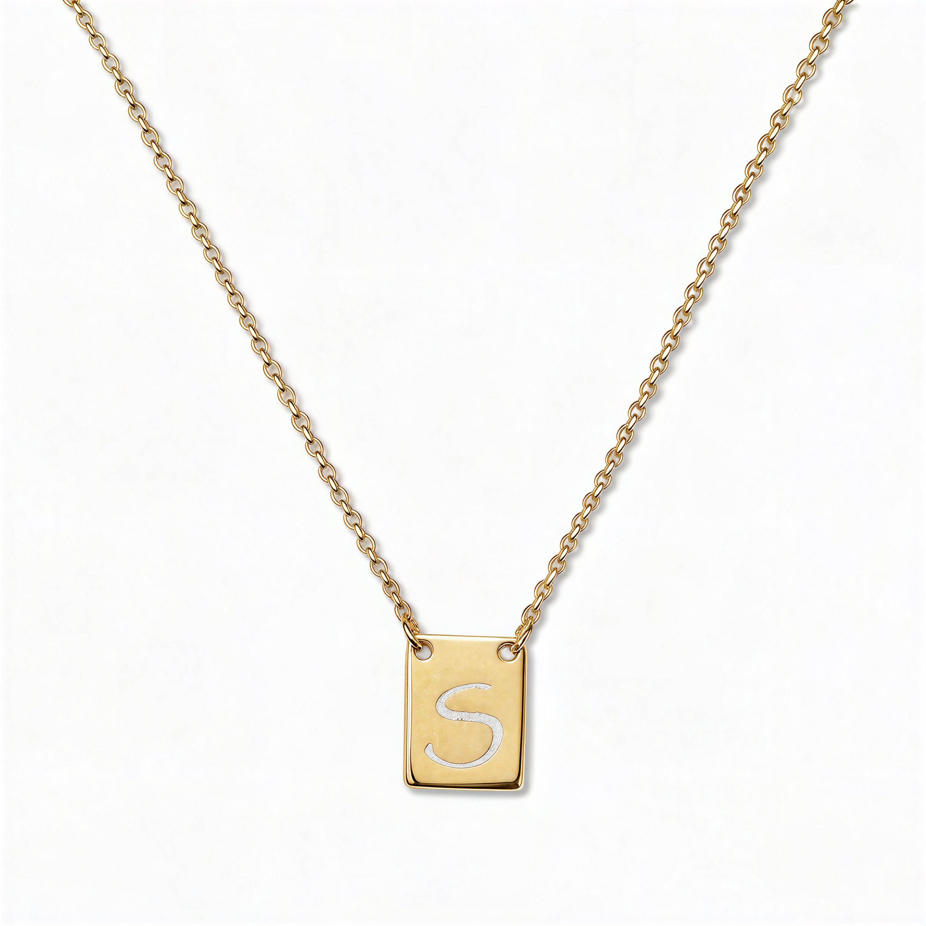 An Engraved Initial Necklace Letter S by Skōsh Jewelry, featuring a small rectangular tag engraved with the letter S on a fine gold chain, displayed against a white background.
