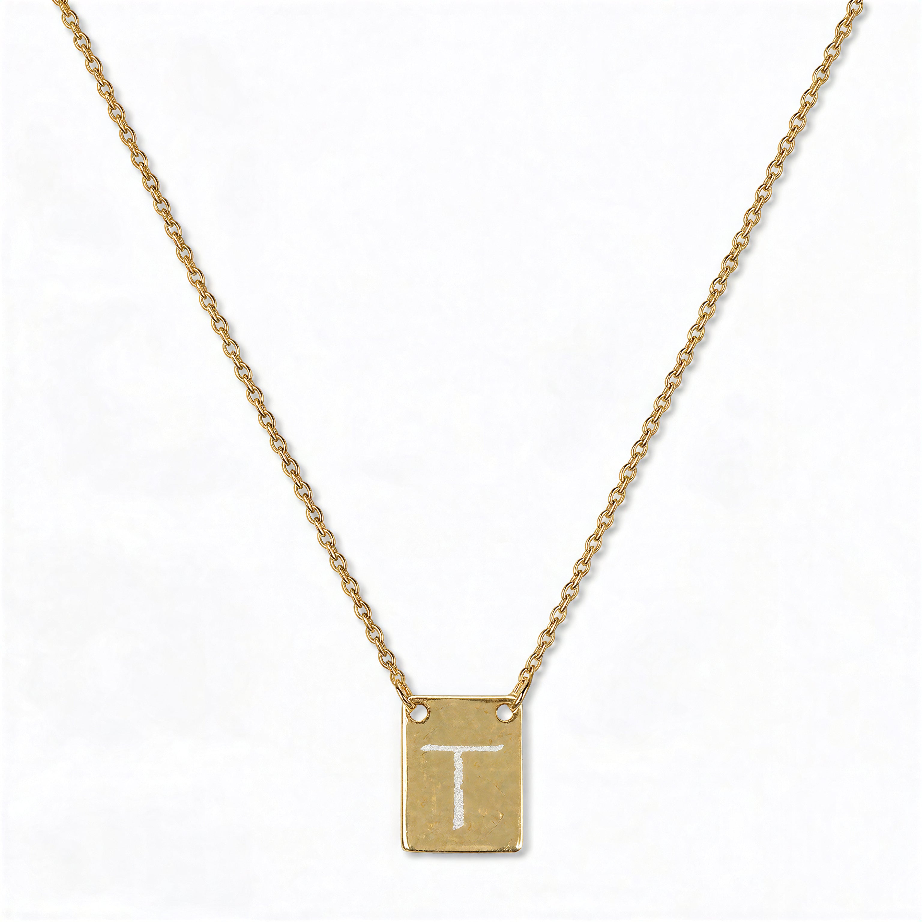 An Engraved Initial Necklace Letter T by Skōsh Jewelry, featuring a small rectangular tag engraved with the letter T on a fine gold chain, displayed against a white background.