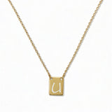 An Engraved Initial Necklace Letter U by Skōsh Jewelry, featuring a small rectangular tag engraved with the letter U on a fine gold chain, displayed against a white background.