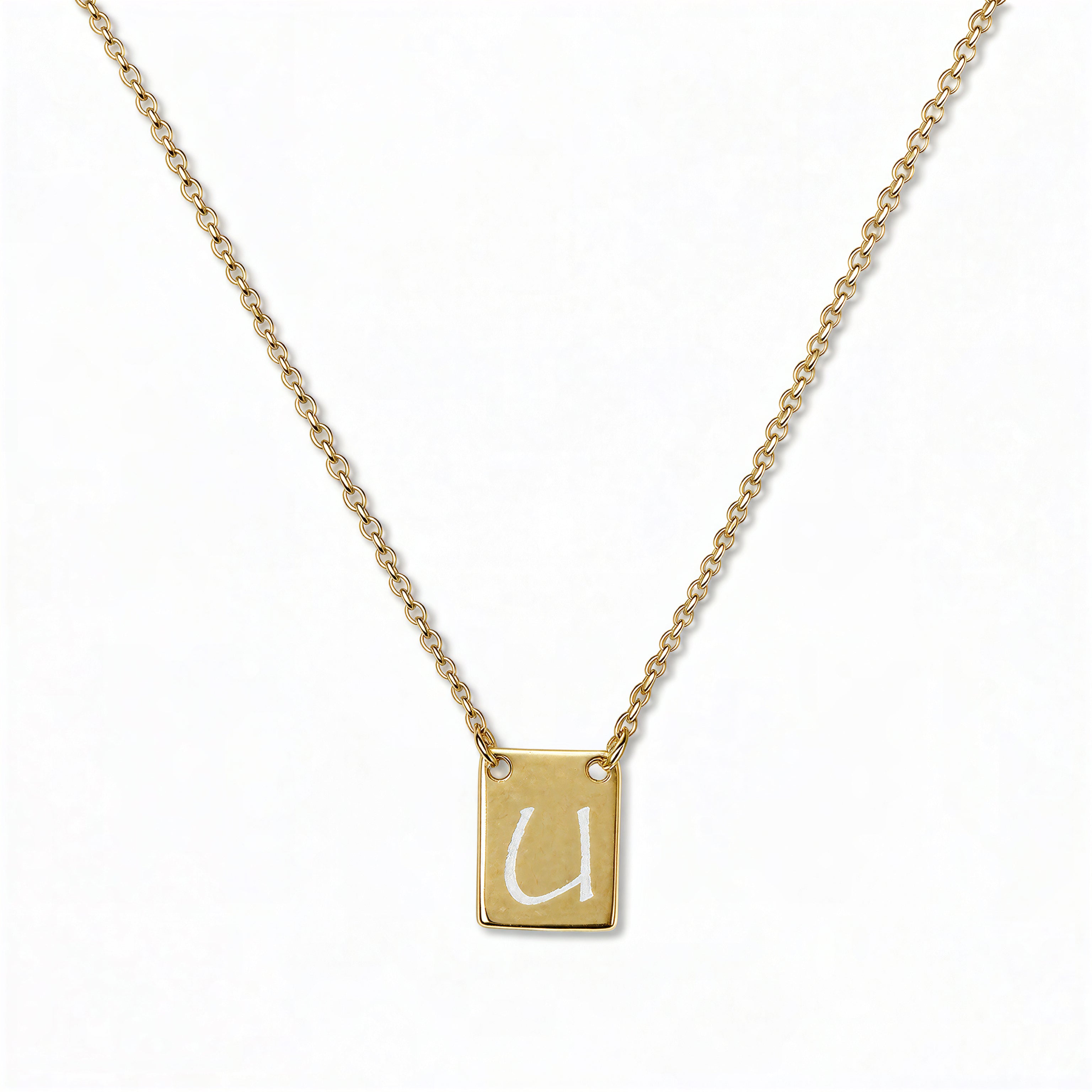 An Engraved Initial Necklace Letter U by Skōsh Jewelry, featuring a small rectangular tag engraved with the letter U on a fine gold chain, displayed against a white background.