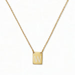An Engraved Initial Necklace Letter W by Skōsh Jewelry, featuring a small rectangular tag engraved with the letter W on a fine gold chain, displayed against a white background.