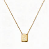 An Engraved Initial Necklace Letter X by Skōsh Jewelry, featuring a small rectangular tag engraved with the letter X on a fine gold chain, displayed against a white background.