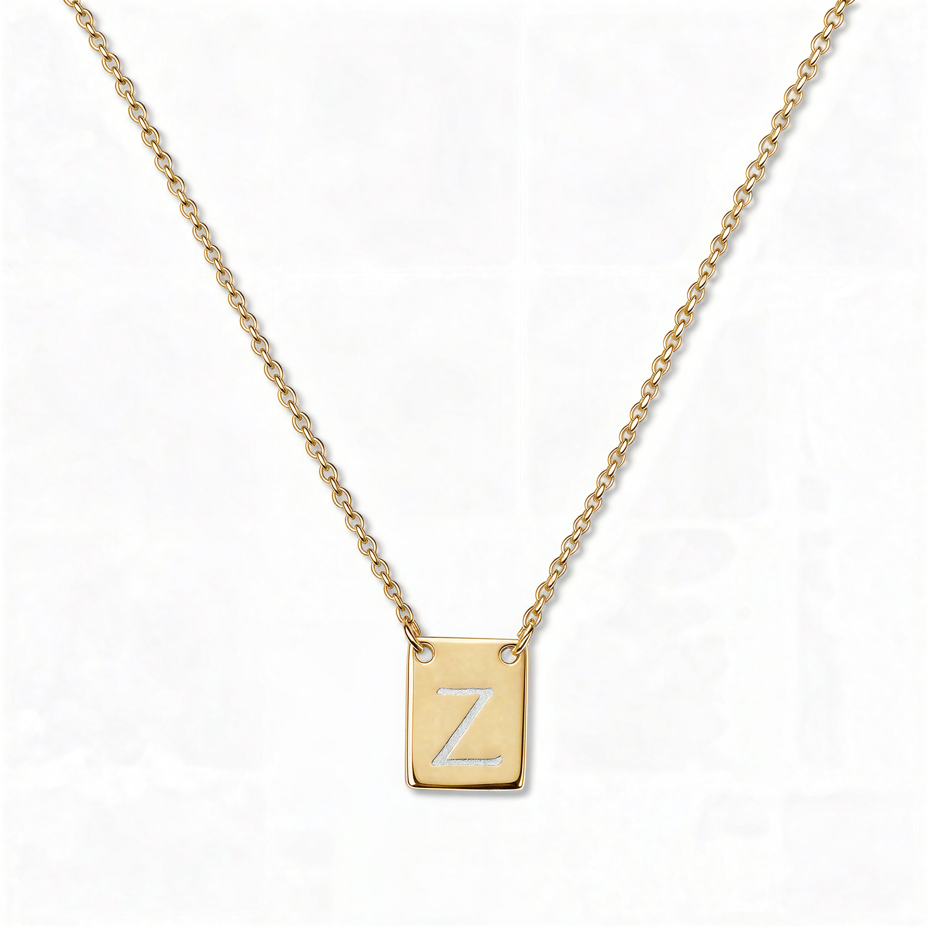 An Engraved Initial Necklace Letter Z by Skōsh Jewelry, featuring a small rectangular tag engraved with the letter Z on a fine gold chain, displayed against a white background.