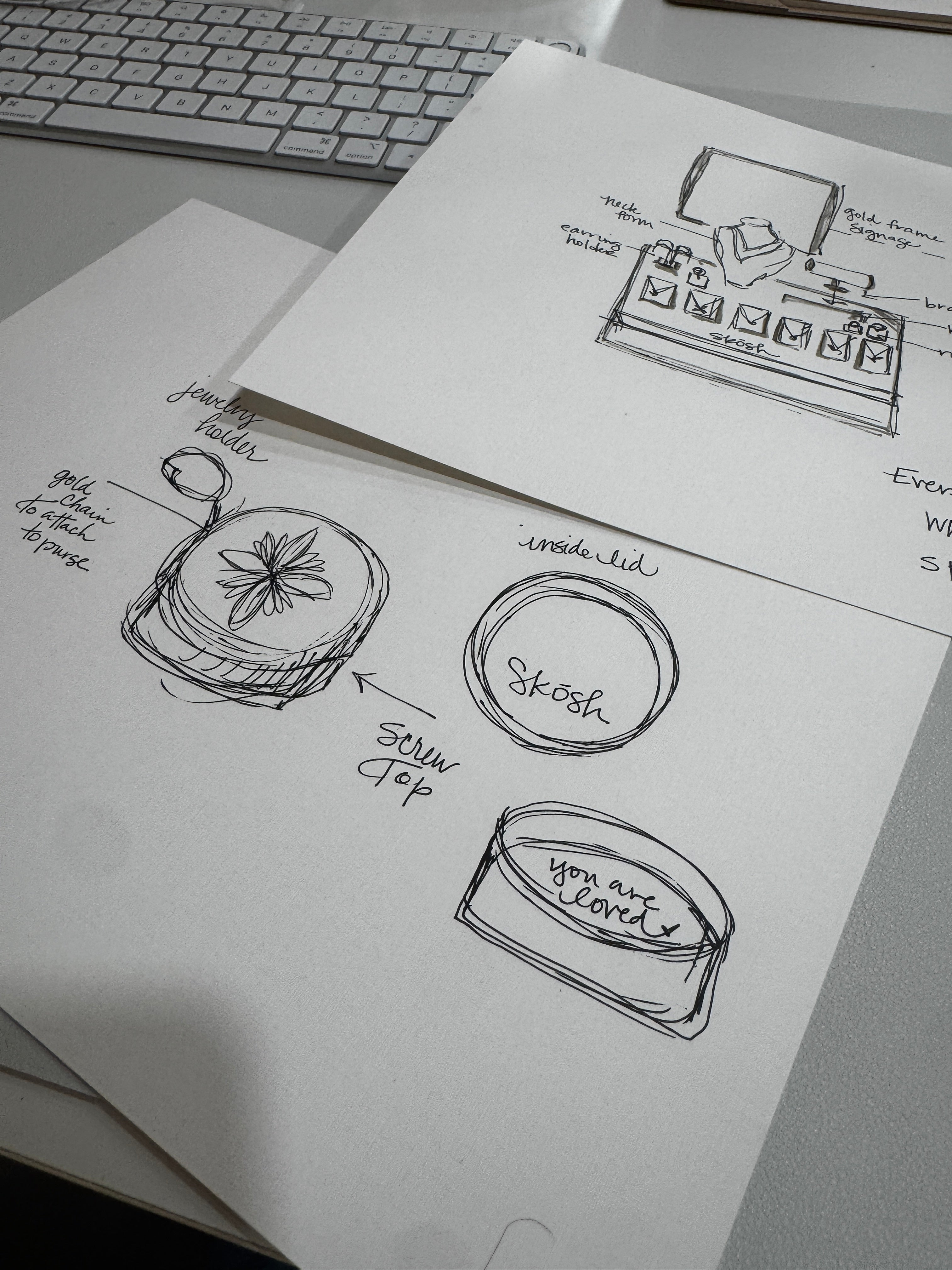 Pencil sketches of pendant designs beside a keyboard