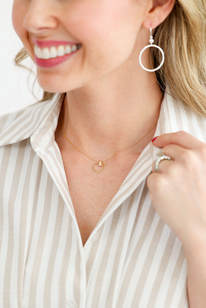 Smiling woman wearing hoop earrings and a dainty necklace by Skōsh Jewelry