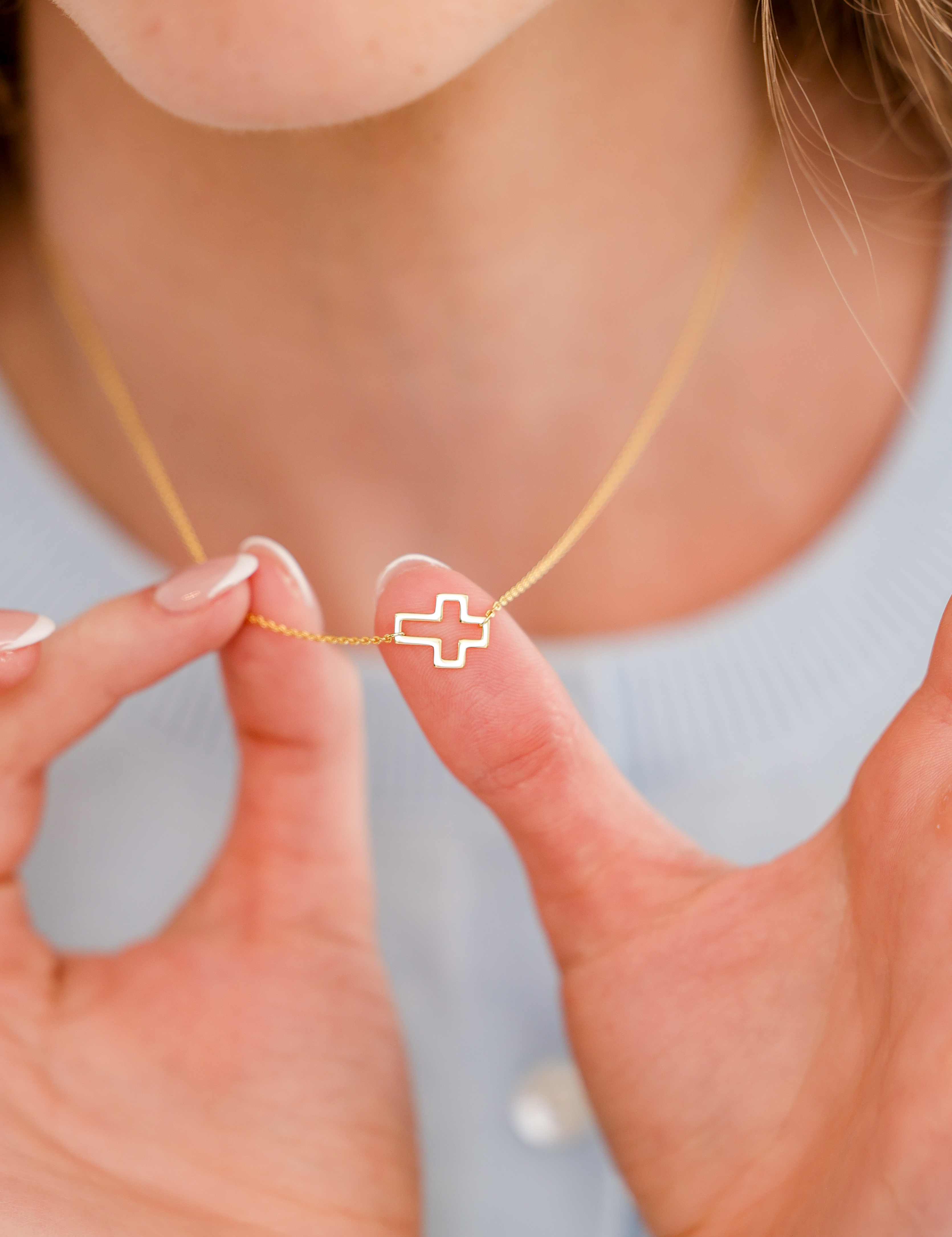 Woman holding a dainty pendant necklace by Skōsh Jewelry at her neckline