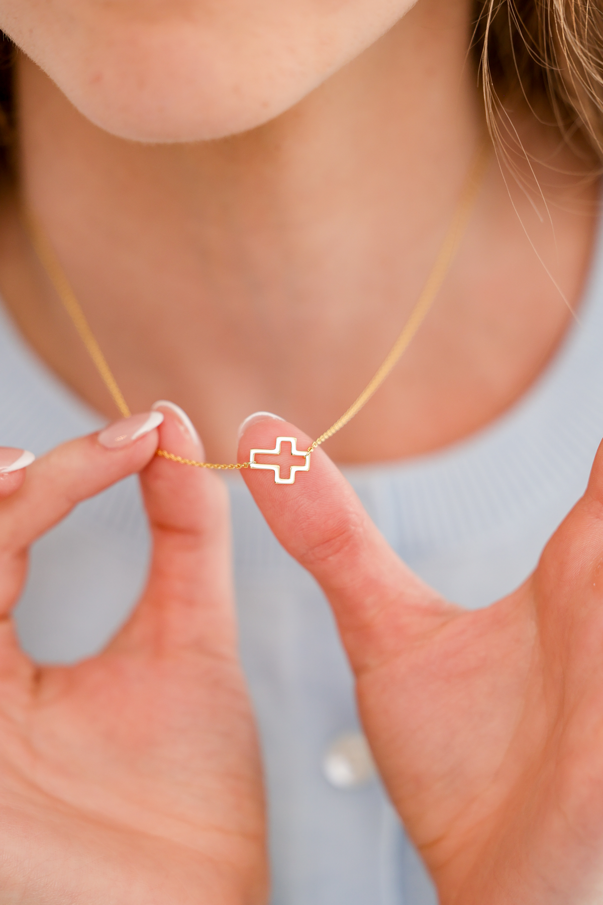 Woman holding a dainty pendant necklace by Skōsh Jewelry at her neckline