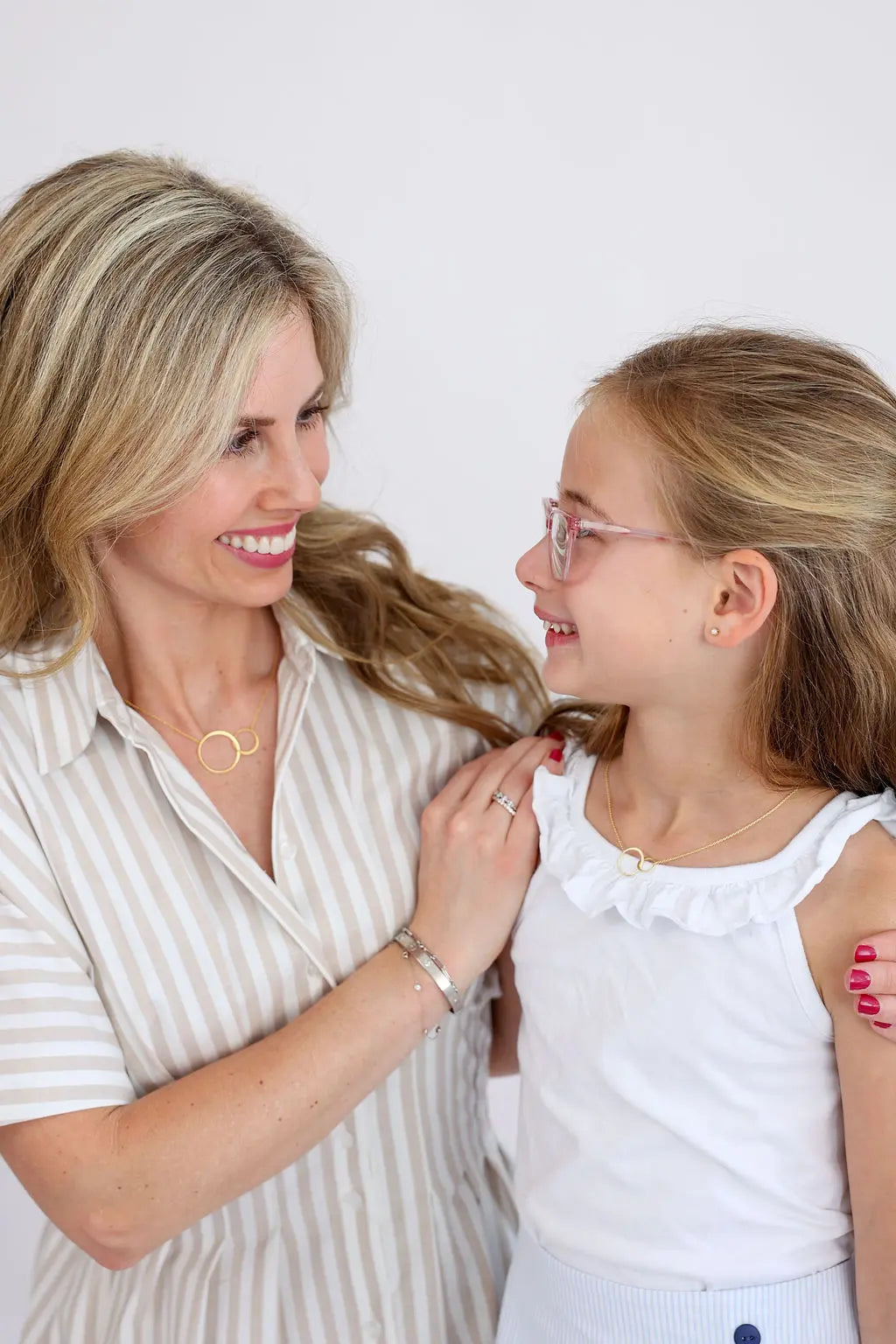 Mother and daughter smiling at each other while wearing Skōsh Jewelry necklaces